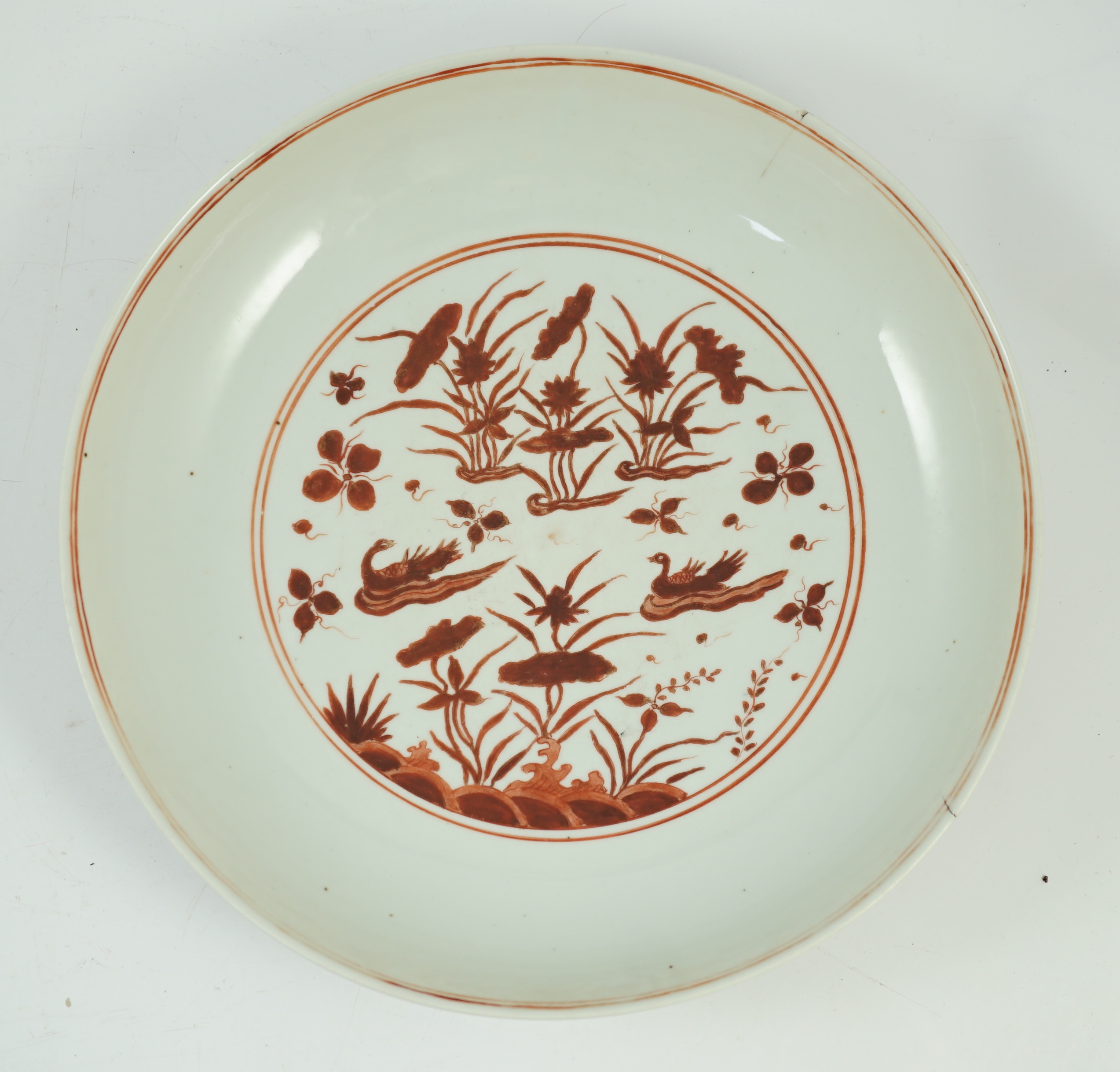 A large Chinese iron red enamelled ‘lotus pond’ dish, Wanli mark and possibly of the period, two short cracks